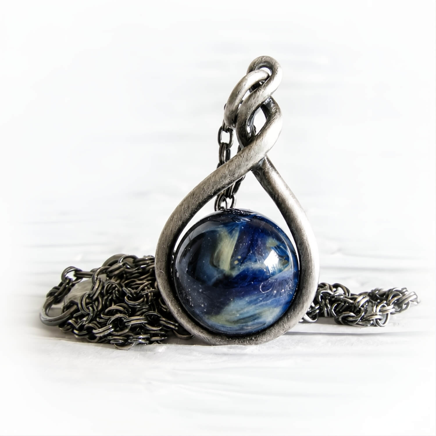 Antiqued sterling silver pendant featuring a hand blown glass marble with ashes permanently encased in the glass