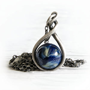 Antiqued sterling silver pendant featuring a hand blown glass marble with ashes permanently encased in the glass