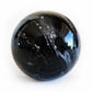 Black artisan blown glass cremation marble swirled with white ashes permanently encased in glass