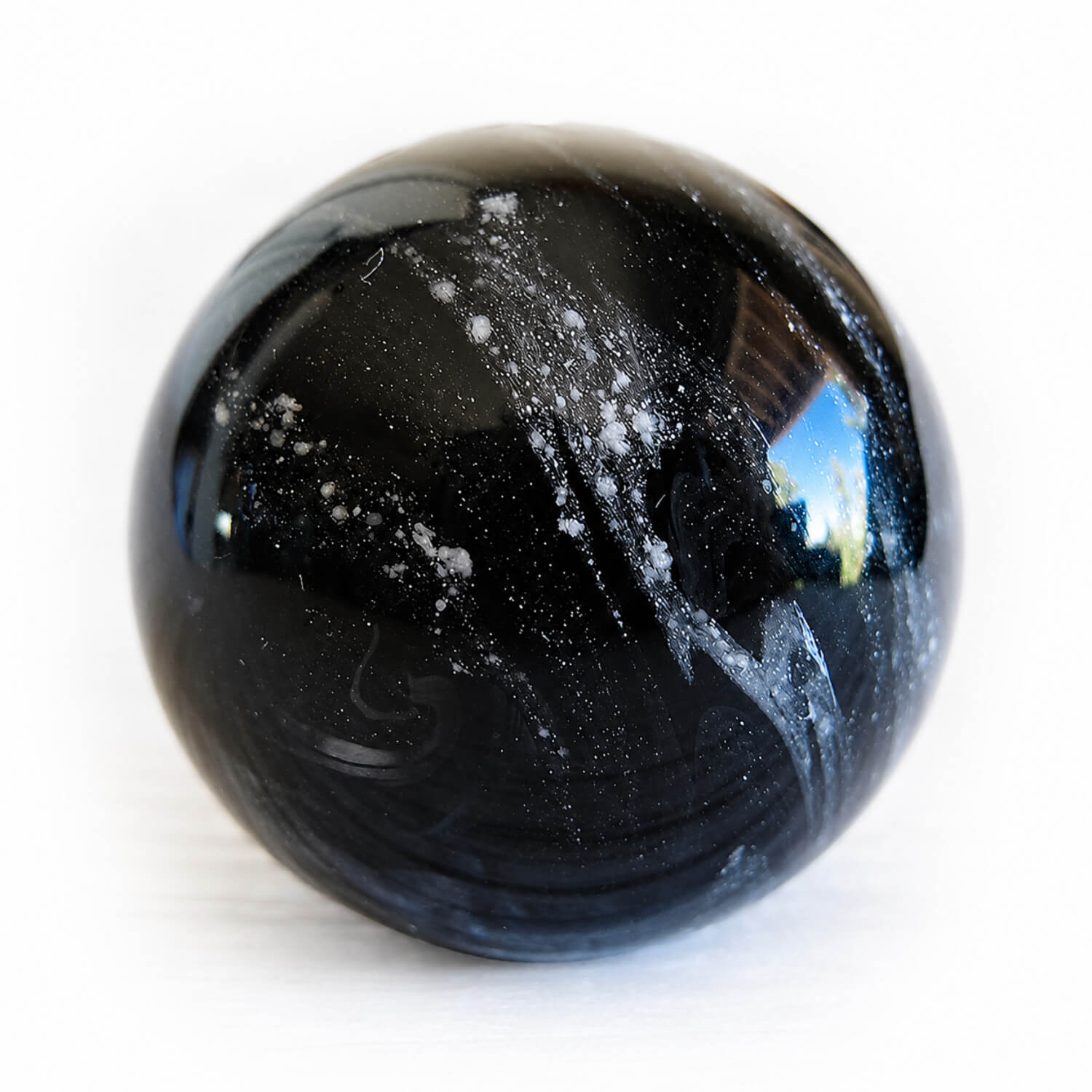 Black artisan blown glass cremation marble swirled with white ashes permanently encased in glass