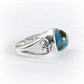 A sterling silver ring featuring a round cremation  glass cabochon gemstone with a marbled blue, green, and brown pattern, displayed on a light gray wood-textured background.