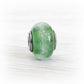 Cremation ashes encased in a hand blown green glass memorial charm bead set on a sterling silver tube with silver end caps with an antique finish
