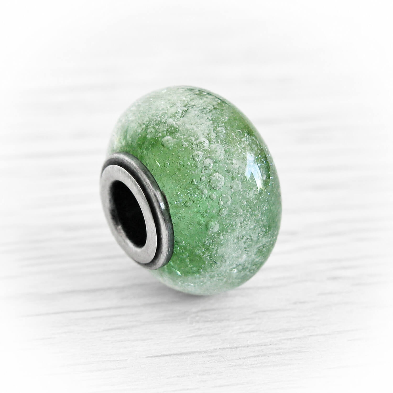 Green artisan made glass cremation charm bead with encased ashes floating over green glass fit onto antique finished sterling silver 