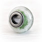 Artisan crafted glass bead with cremation ashes encased and floating over green glass set on dark oxidized sterling silver center