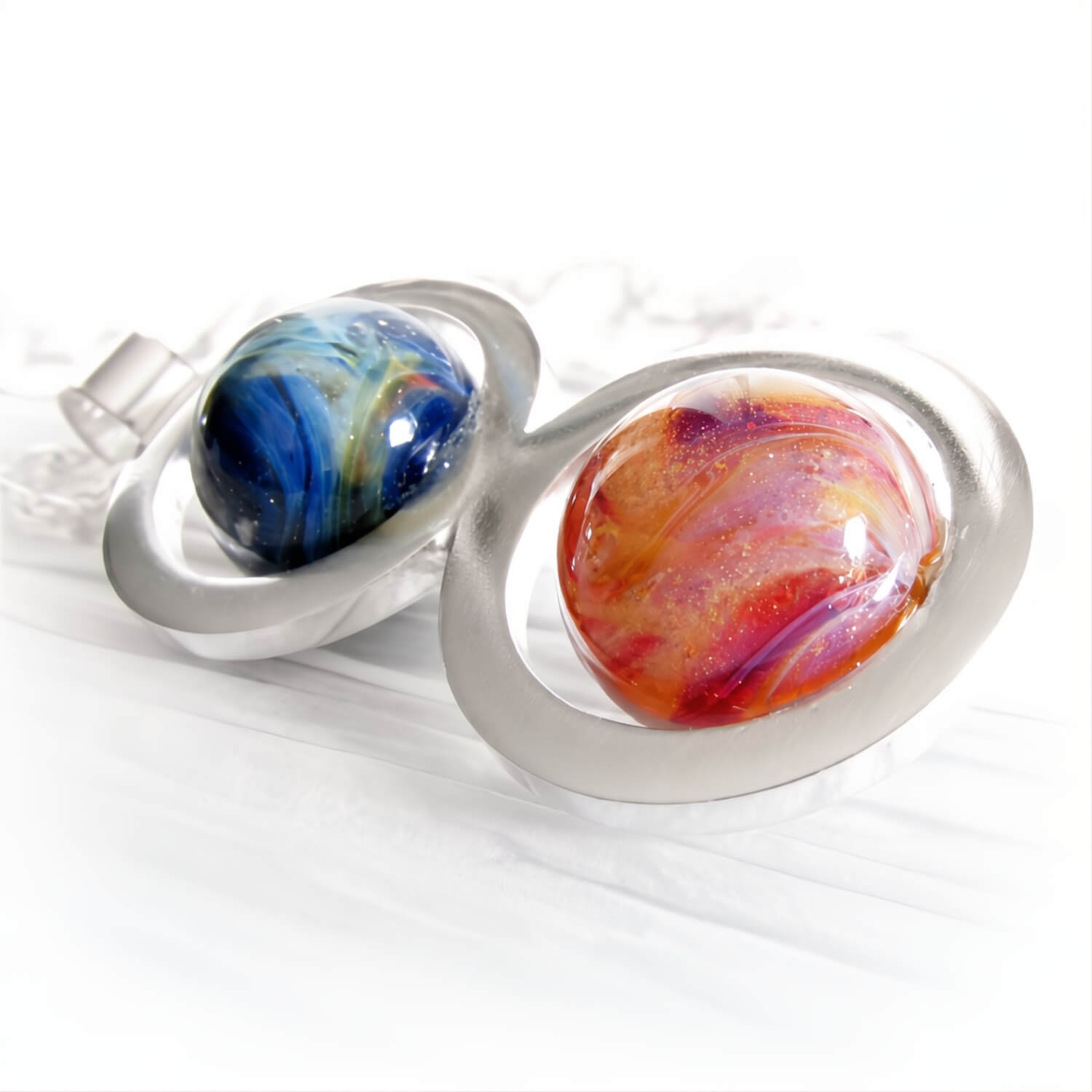 Colorful hand crafted glass marbles with swirls of cremation ashes mounted in a sterling silver pendant