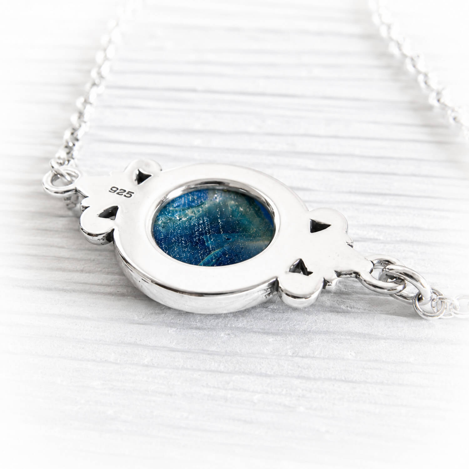Back of a sterling silver memorial pendant hallmarked .925 with a blue hand blown glass cabochon