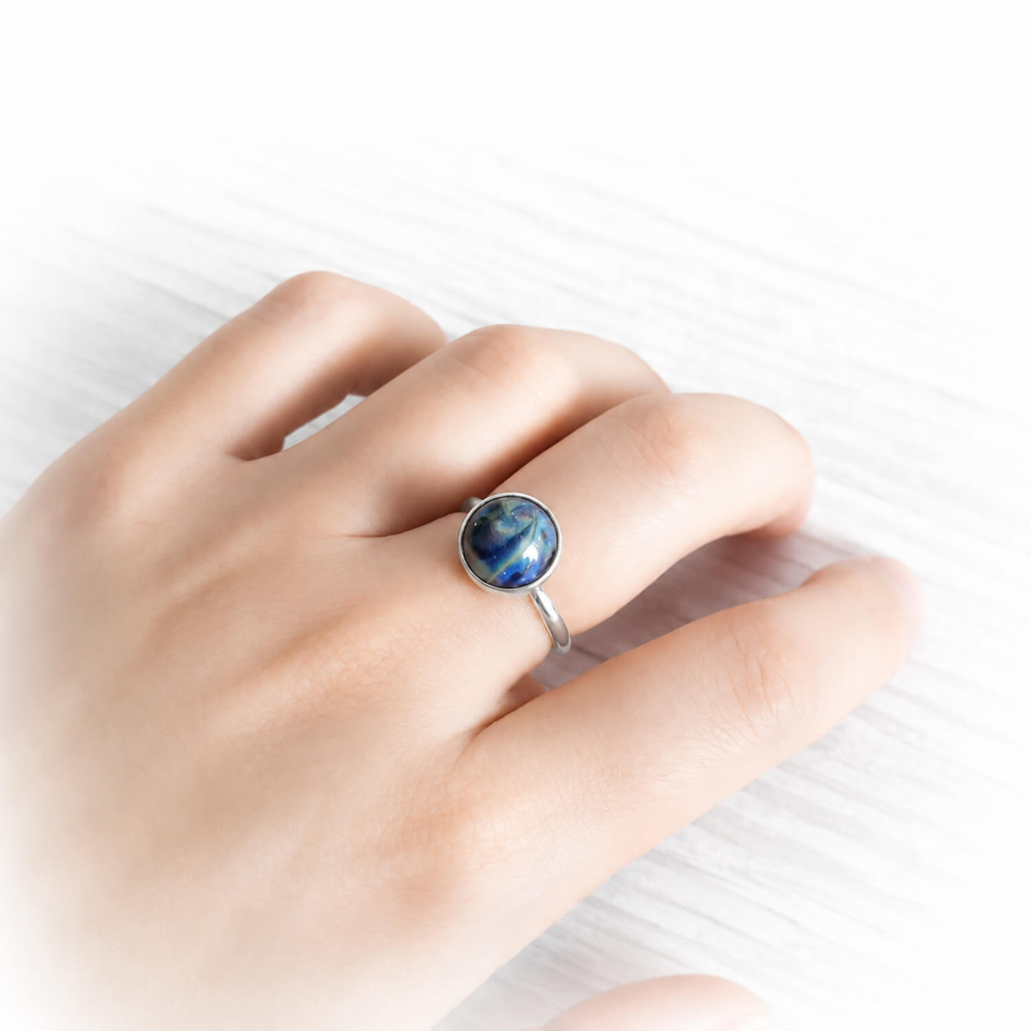 Dainty minimalist memorial ring with cremation ashes swirled in colorful hand blown glass on a models hand