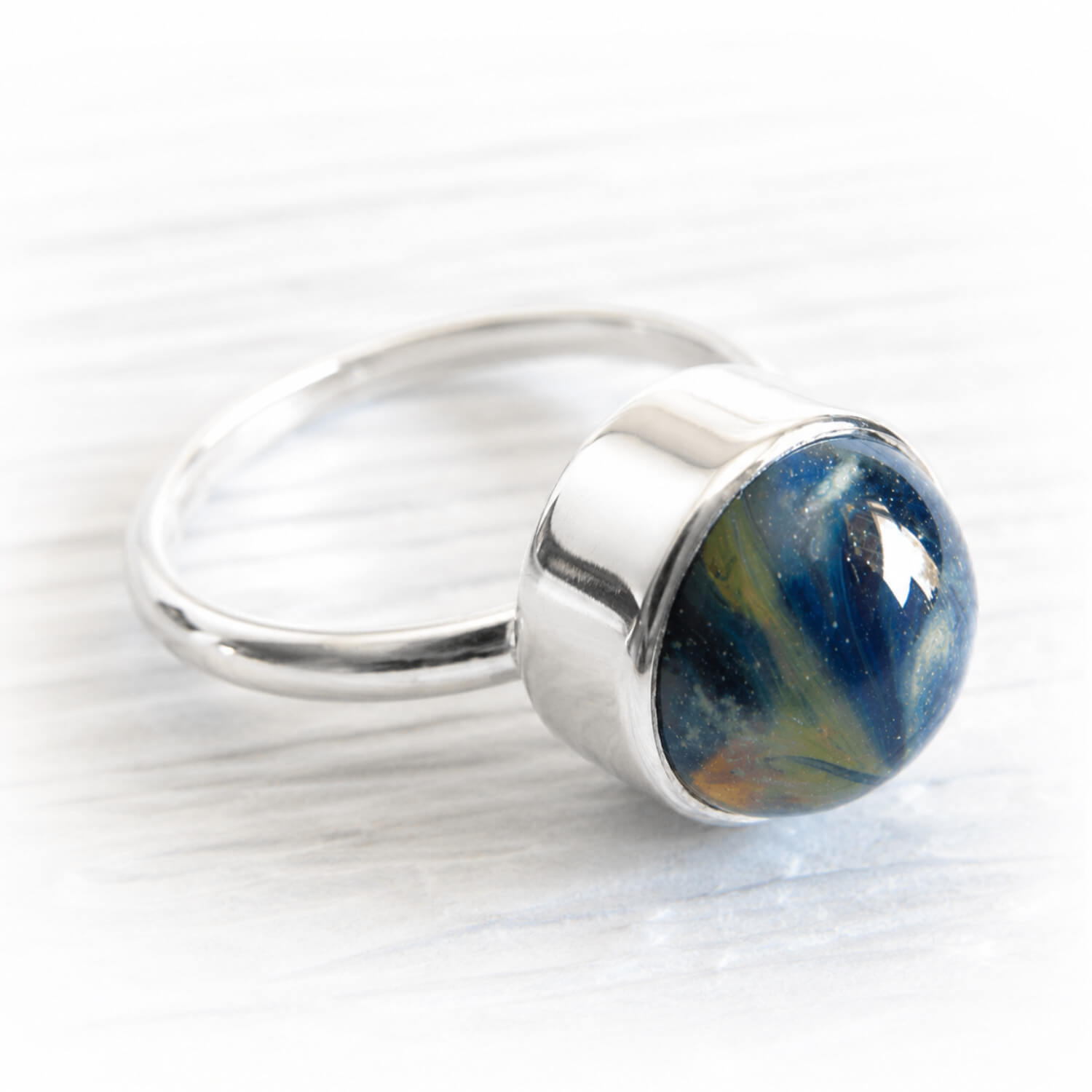 Hand blown blue and green glass swirled with cremation ashes set into a sterling silver memorial ring