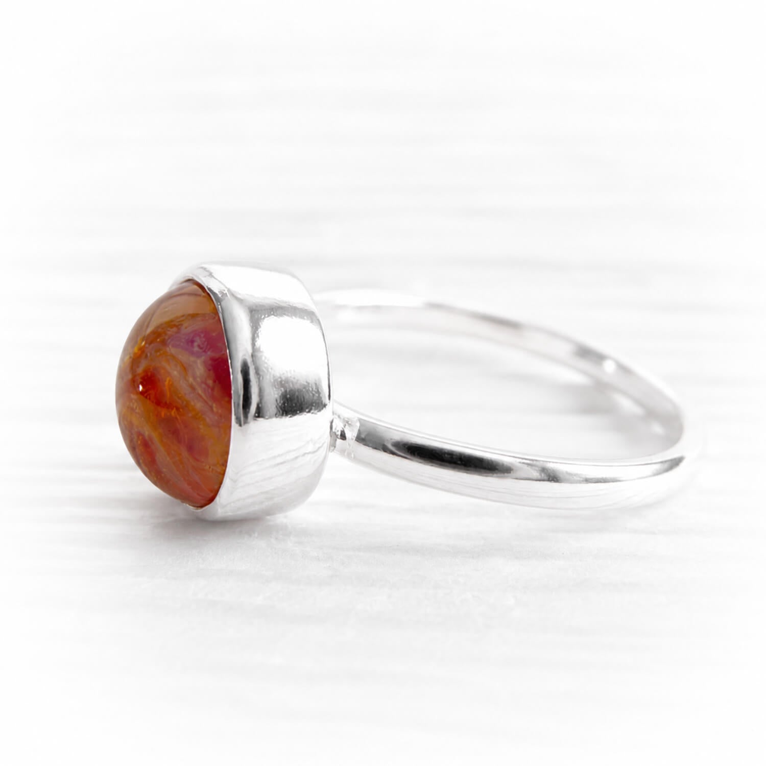 Polished sterling silver memorial ring featuring a hand blown glass gem with ashes permanently encased in glass 