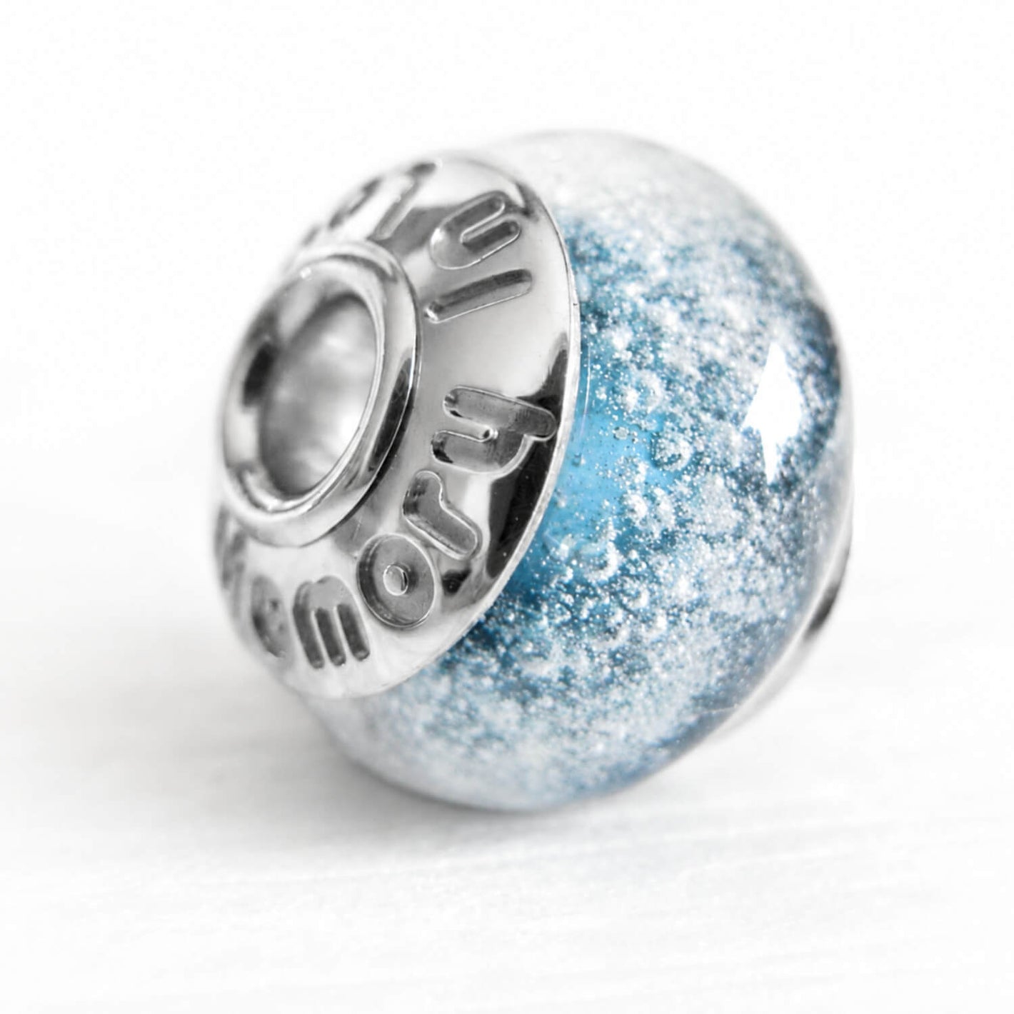 Light blue memorial bead with custom engraved sterling silver bead caps on a white background