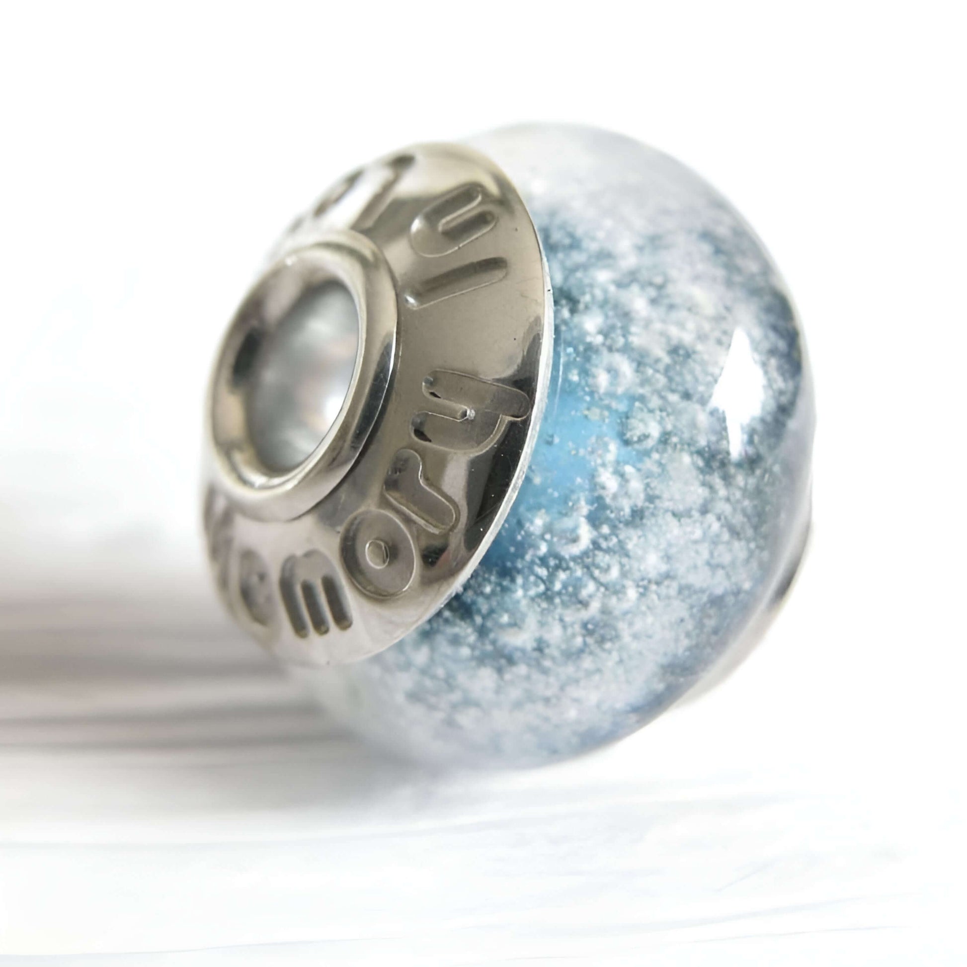 Light blue memorial bead with custom engraved sterling silver bead caps on a white background