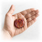 Hand holding a red and orange artisan crafted glass memory stone keepsake infused with cremation ashes