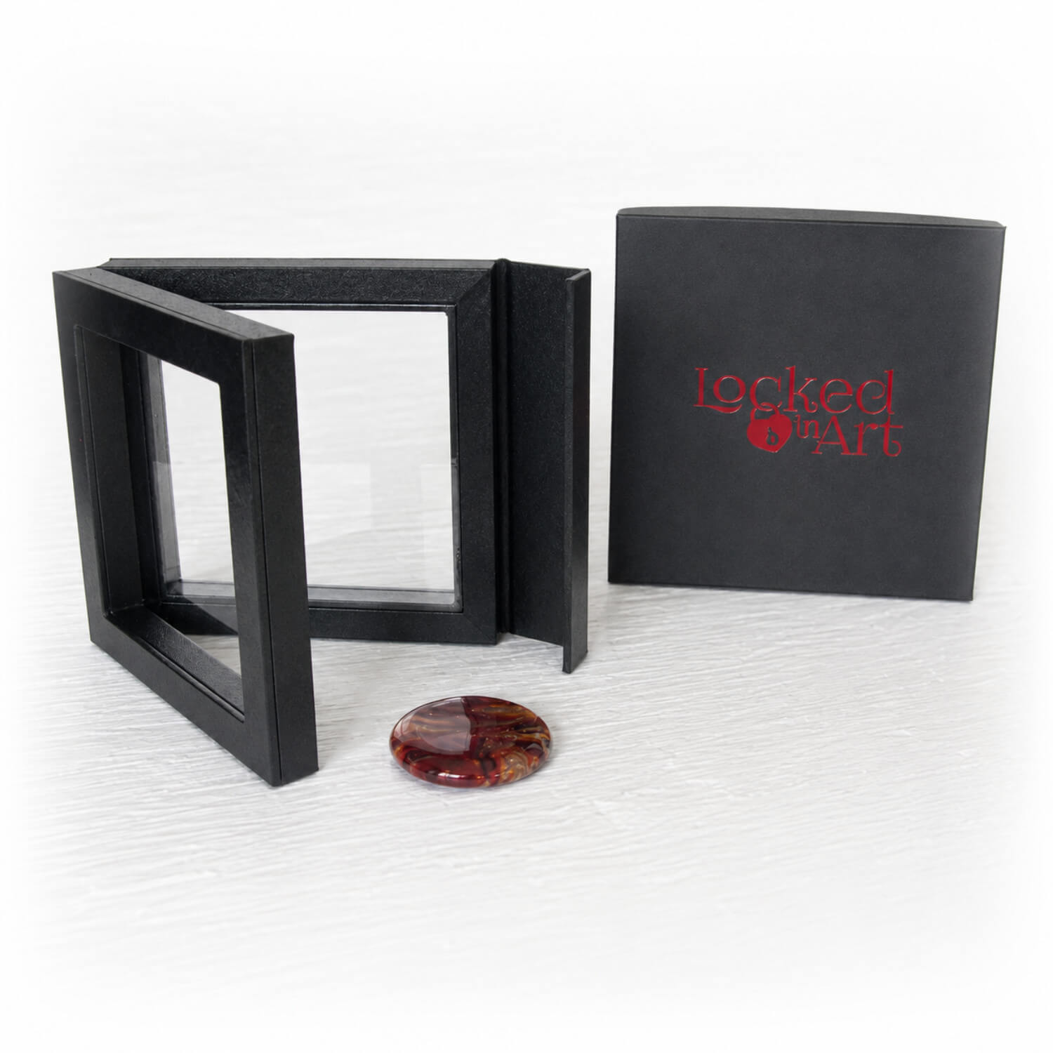 Black jewelry box with 'Locked in Art' branding, open to reveal a red and orange memory stone 