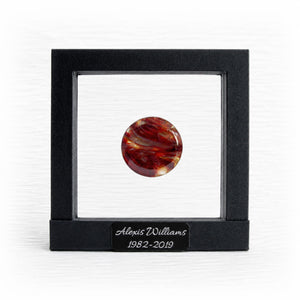 Round red and orange marbled memory stone in a black suspension frame with a personalized engraved nameplate