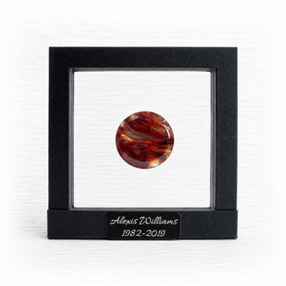 Round red and orange marbled memory stone in a black suspension frame with a personalized engraved nameplate