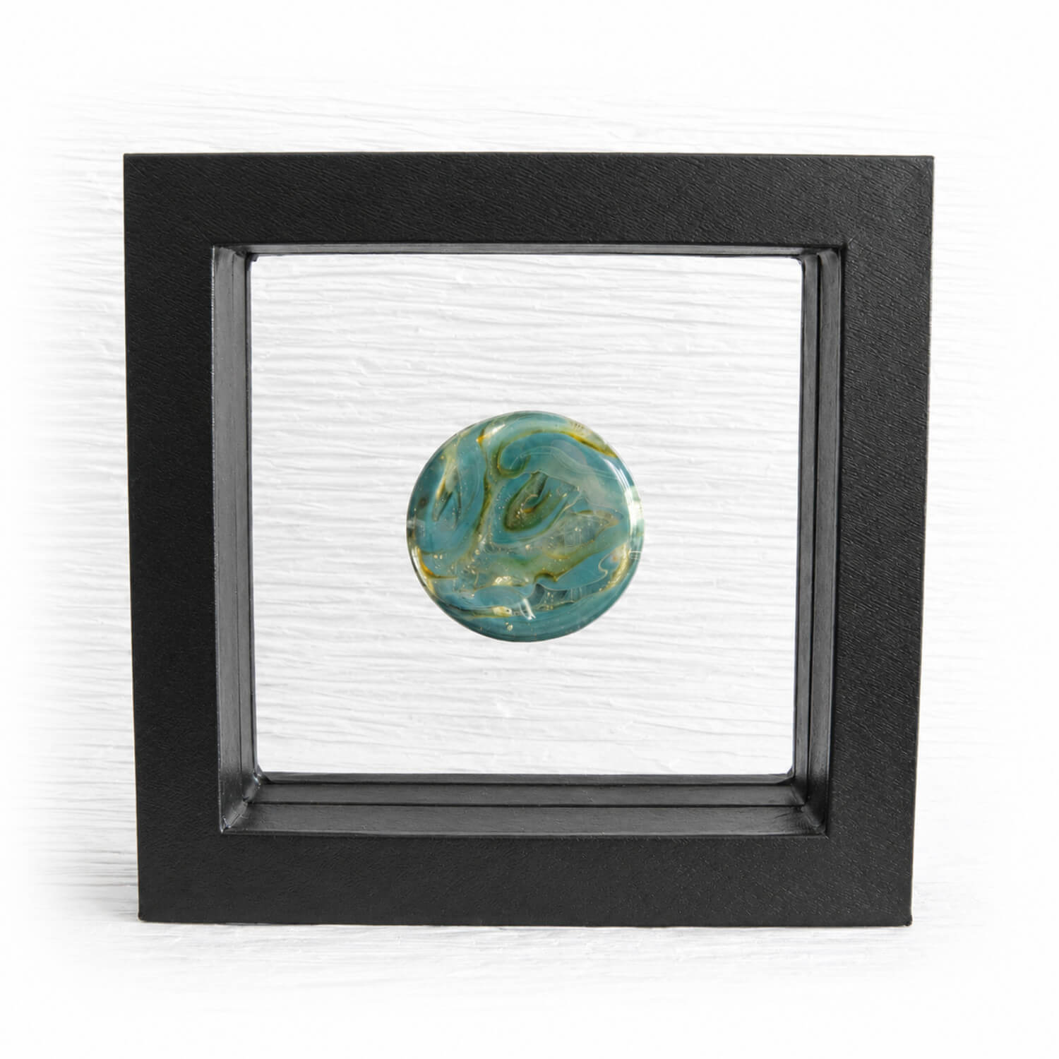 Hand blown aqua and green glass cremation memory stone in a black suspension frame
