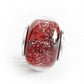 Red hand blown glass cremation bead with silver accents on a white background