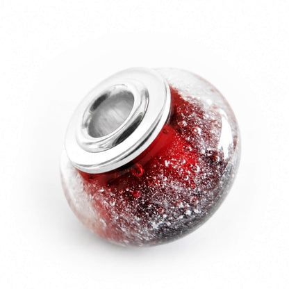 Red hand made glass cremation bead with sterling silver end caps on a white background 