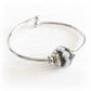 Hand blown glass memorial bead with customized engraving paired with a sterling silver bangle bracelet