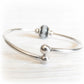 Removable ends on a sterling silver memorial bracelet with a glass cremation bead in the background