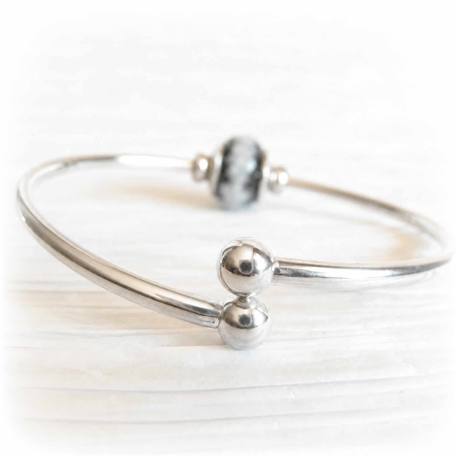 Removable ends on a sterling silver memorial bracelet with a glass cremation bead in the background