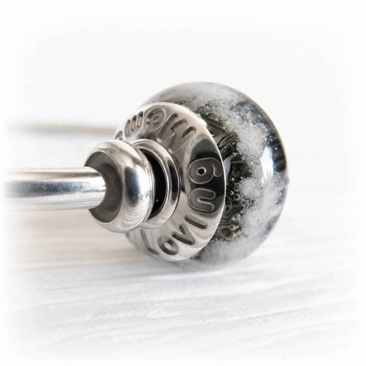 Glass bead handcrafted with cremation ashes together with custom engraved bead caps