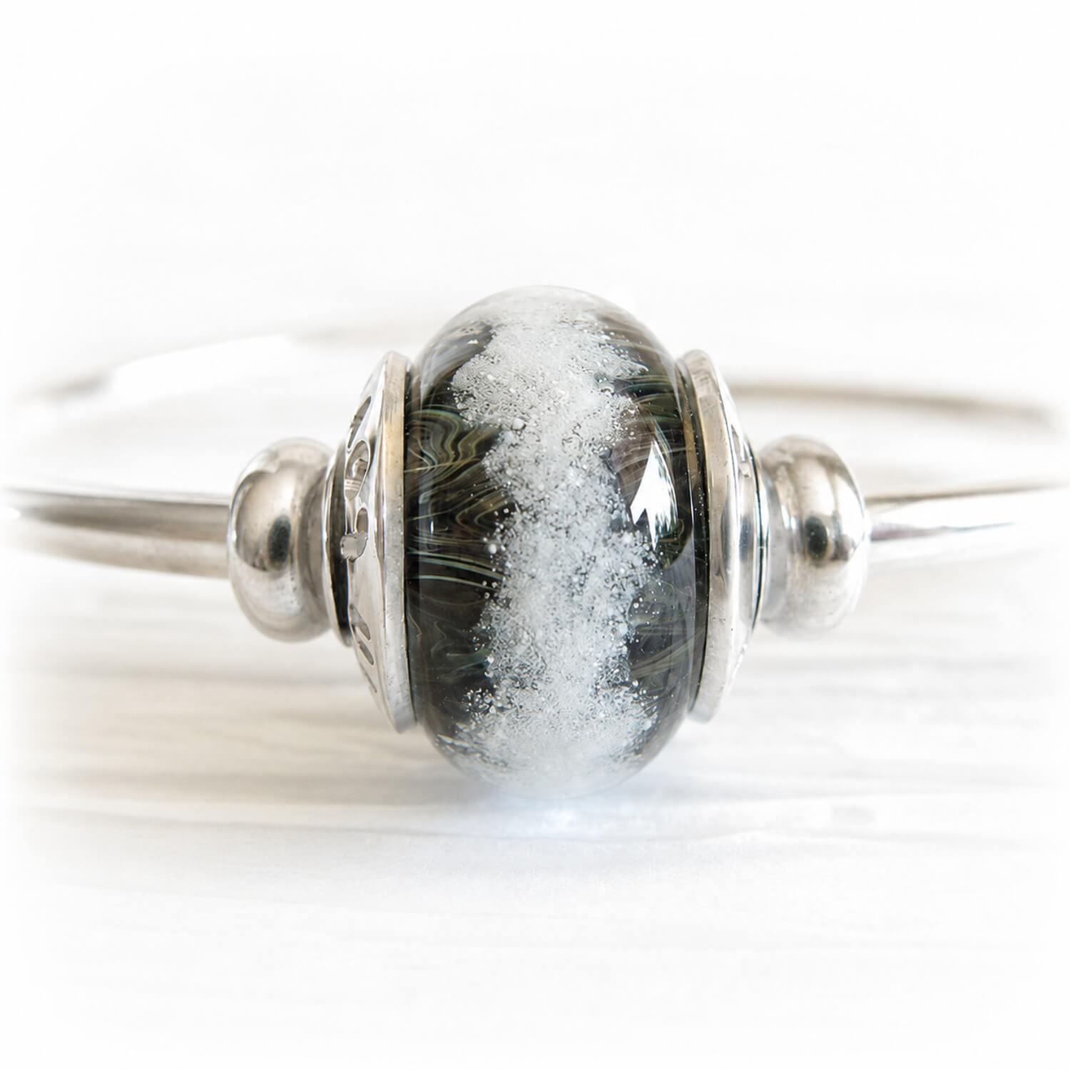 Ashes permanently encased in a hand crafted glass bead displayed on a sterling silver bangle bracelet