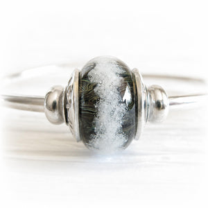 Ashes permanently encased in a hand crafted glass bead displayed on a sterling silver bangle bracelet