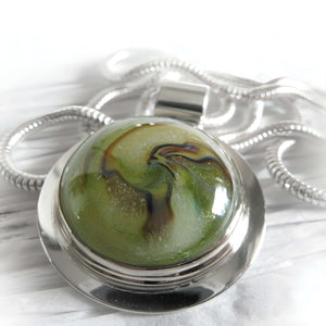  Green and brown cremation ash glass cabochon pendant necklace in a silver setting on a white background