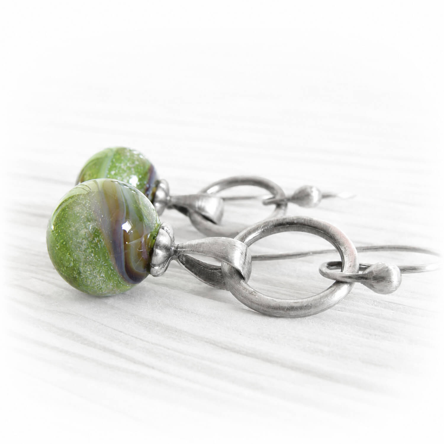 Small green glass marbles with cremation ashes sealed within the glass on sterling silver earring hooks 