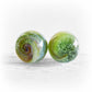 Pair of green glass memorial marbles infused with swirls of pet ashes 