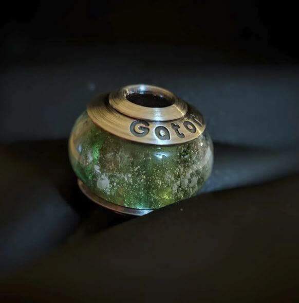 Green glass bead with a sterling silver bead cap Gator on a dark background