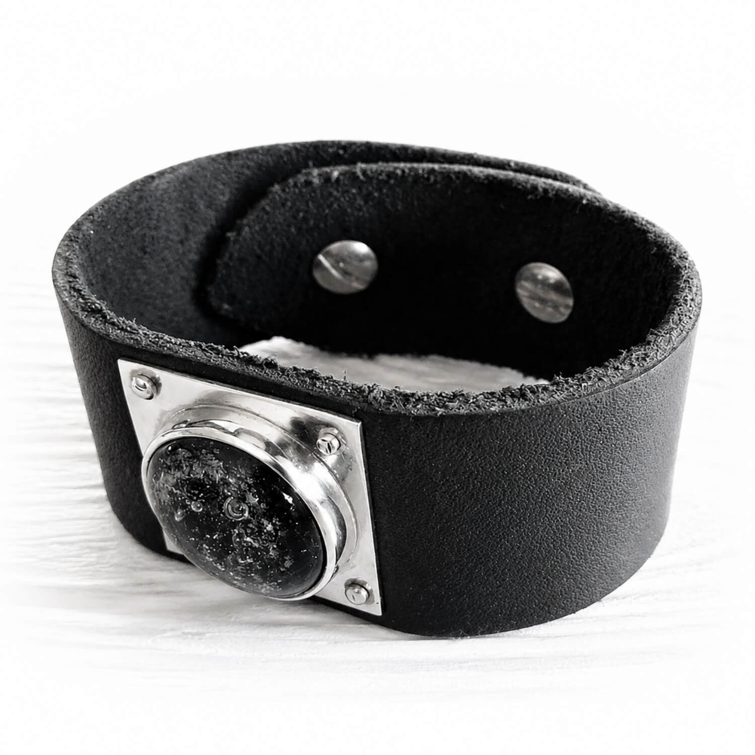 Black leather cuff bracelet with sterling silver accents featuring handcrafted black glass with cremation ashes