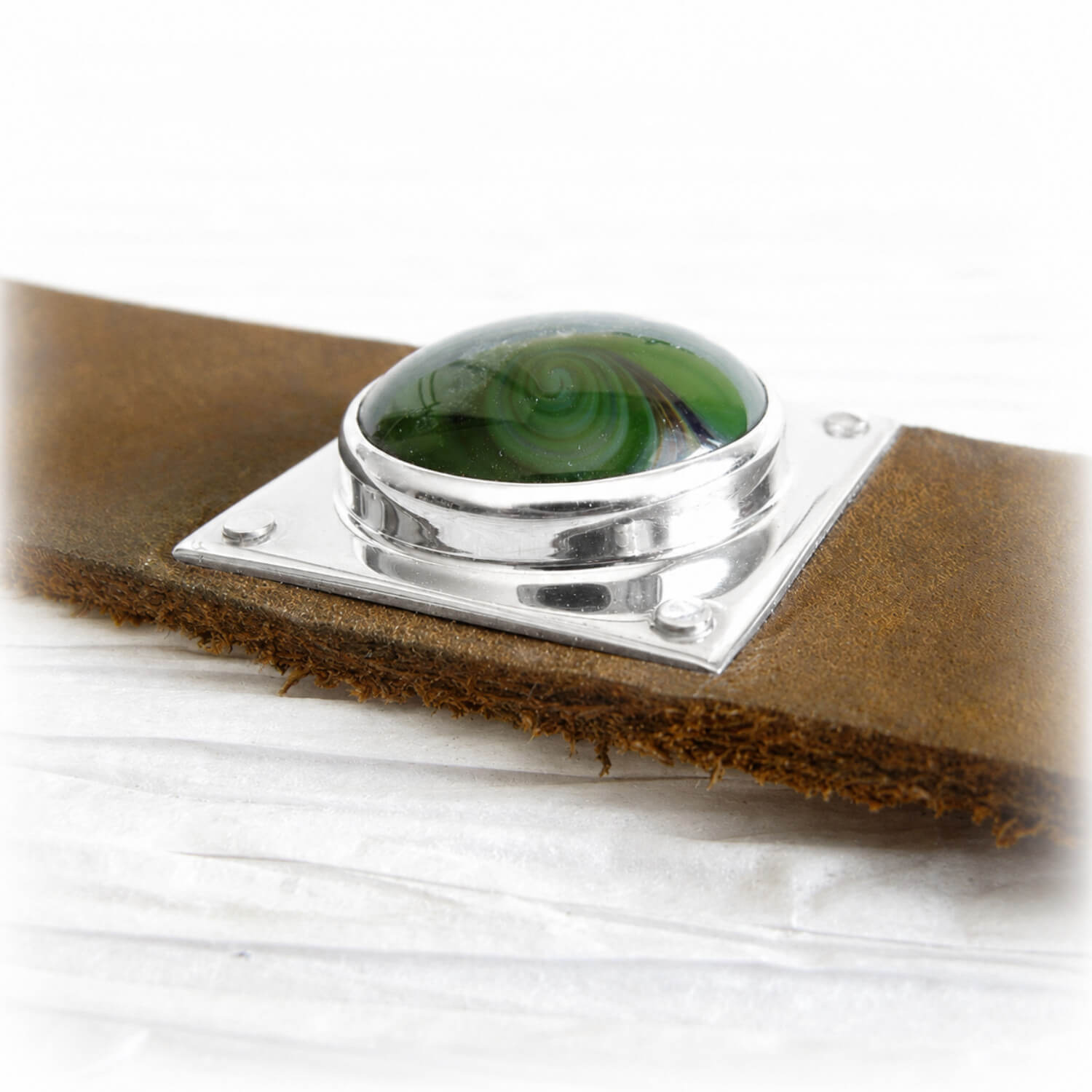 Handmade green memorial glass containing ashes set in sterling silver on a brown leather cuff bracelet 