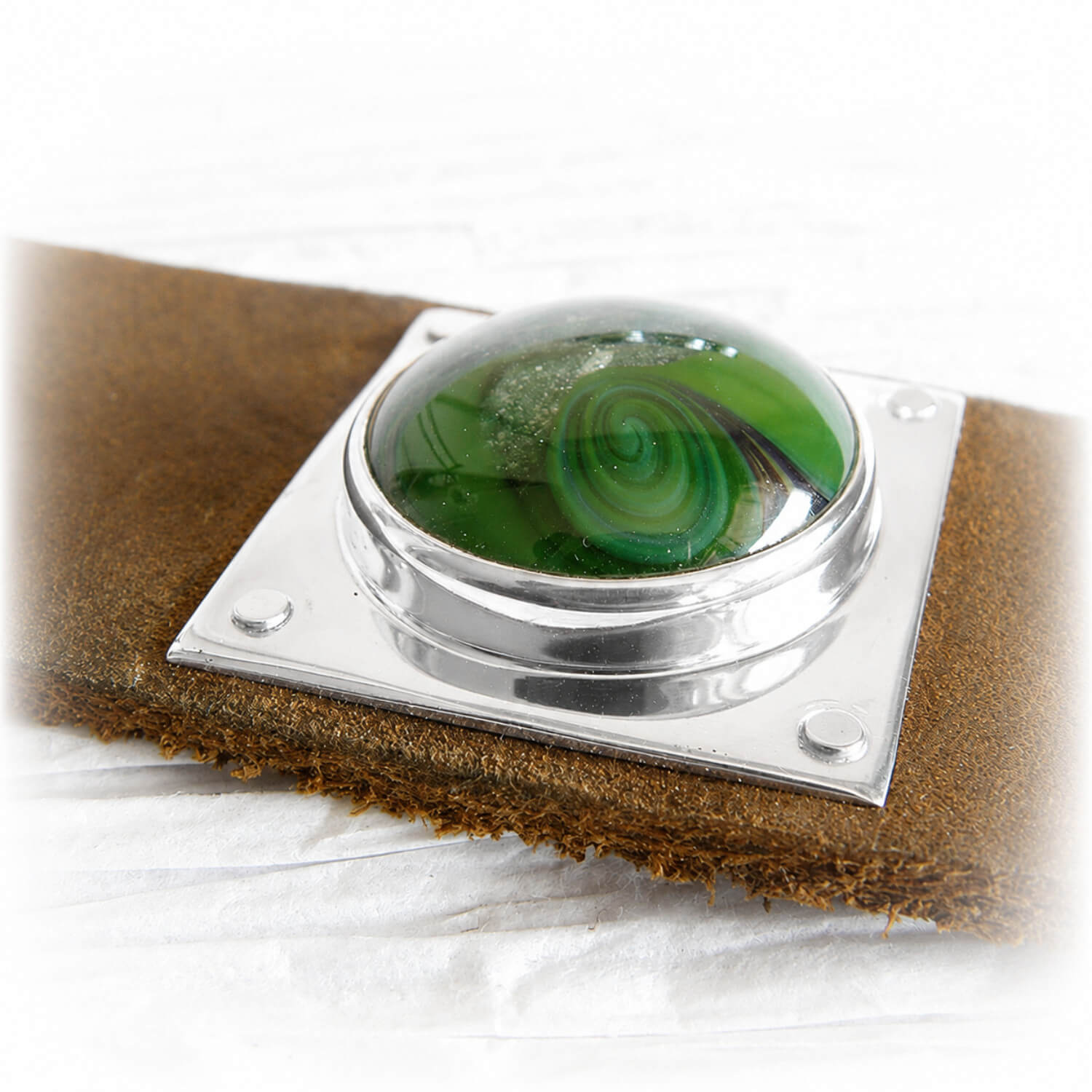 Brown leather memorial cuff bracelet with ashes suspended within swirls of hand blown green glass mounted in sterling silver