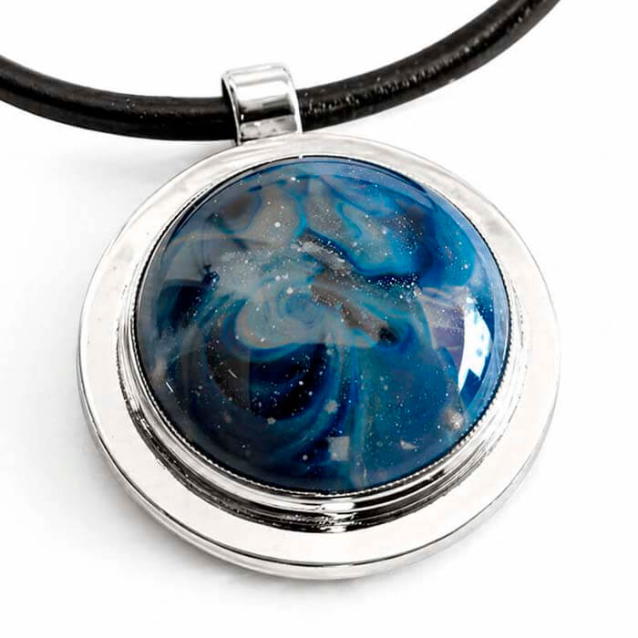 Necklace with a round pendant featuring blue and white cremation ash glass cabochon on a white background