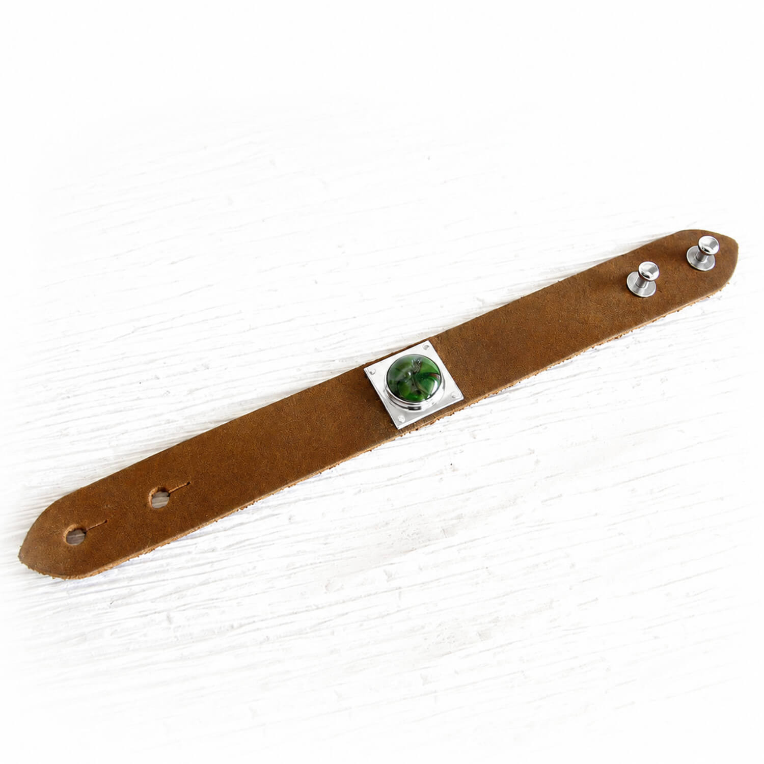 Brown leather cremation bracelet with floating ashes visible within swirls of green and brown artisan glass