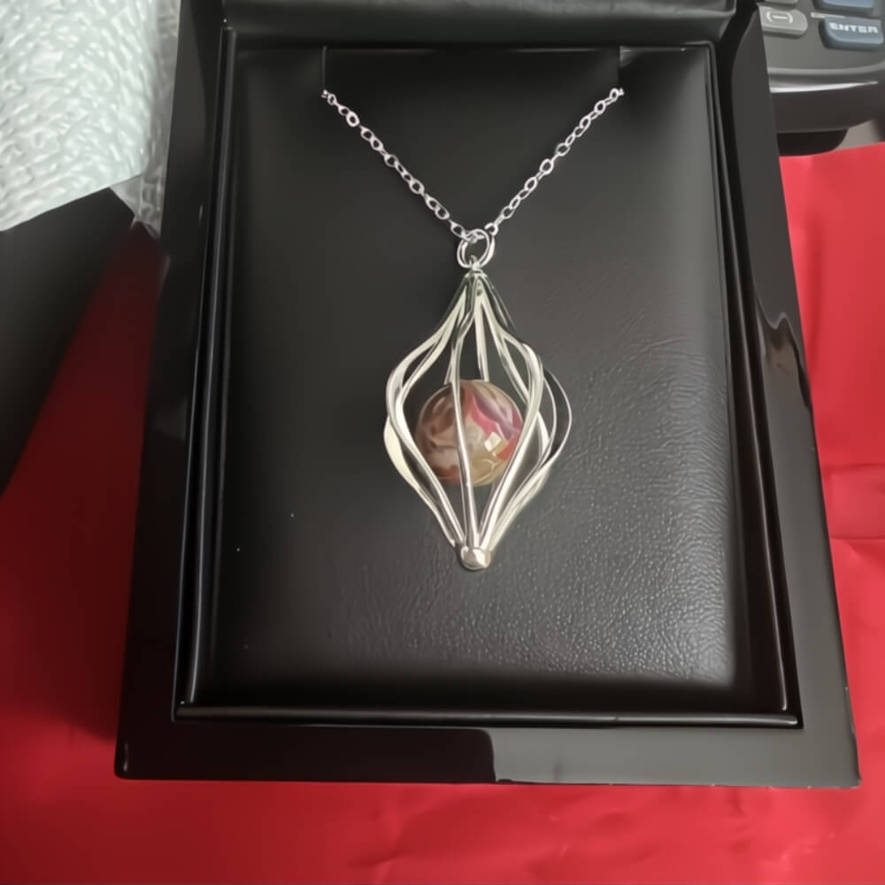 Sterling silver cage pendant with a red memorial marble in a black jewelry box