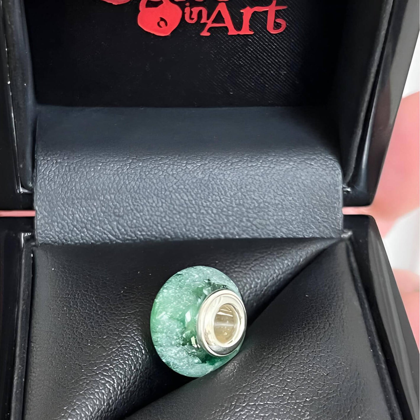 Green glass memorial bead with silver base in a black leather jewelry box branded Locked In Art