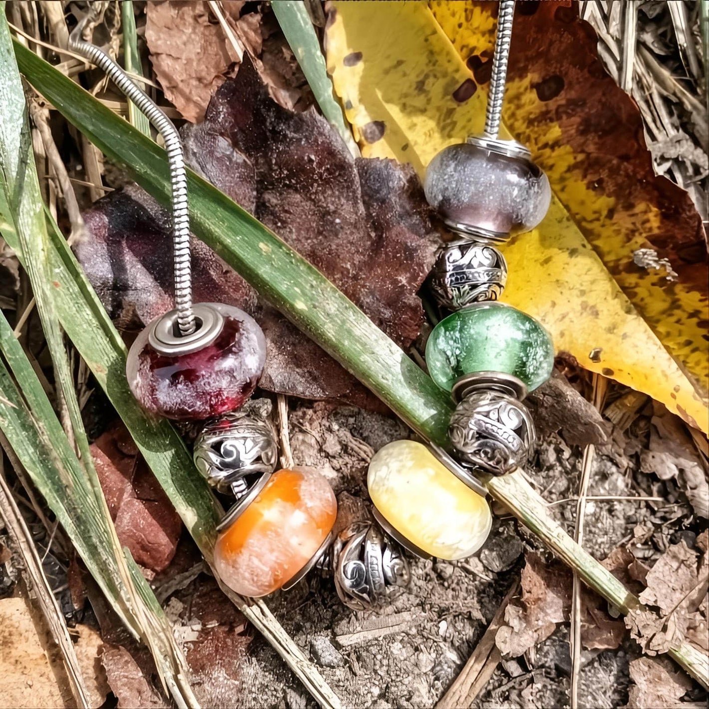 Colorful glass memorial beaded necklace on a natural background with leaves and grass.