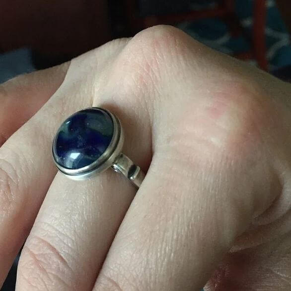 Silver ring with a blue stone on a person's finger