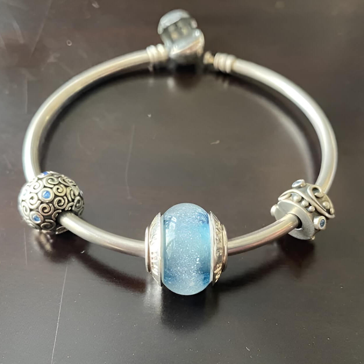 Silver bracelet with blue hand blown glass cremation bead on a dark surface
