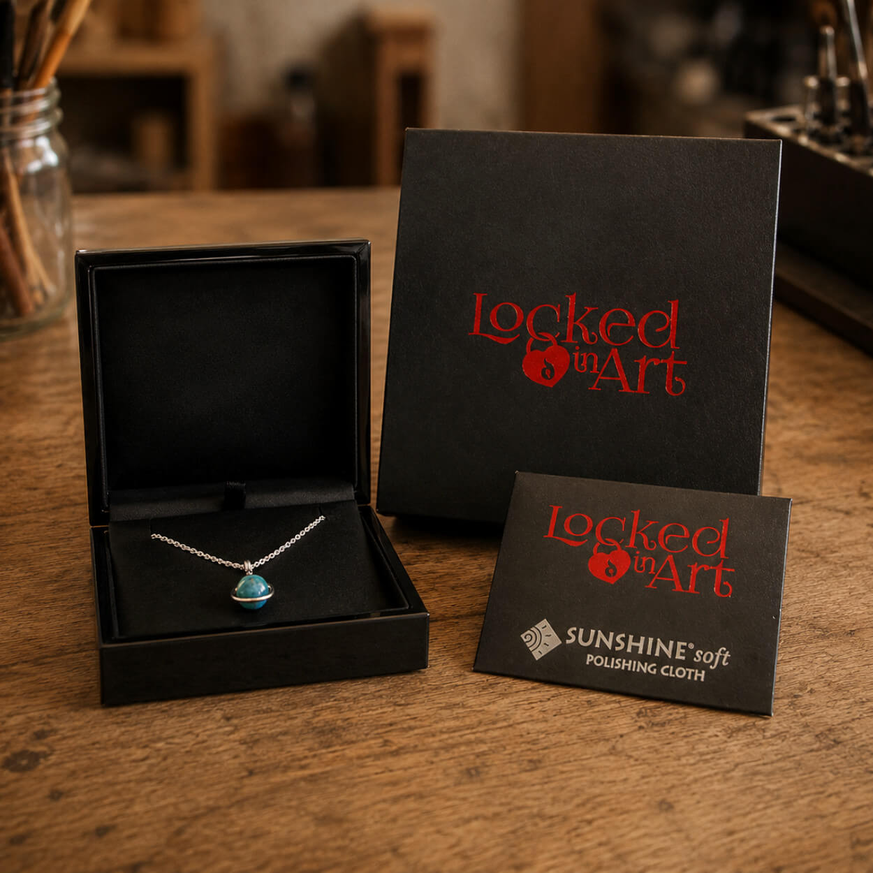 Sterling silver memorial necklace with a turquoise glass marble in an open black box with 'Locked in Art' branding on a wooden surface.