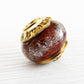 Swirls of dark red and orange hand blown glass under white specks of white ash set with 14k gold custom engraved bead caps