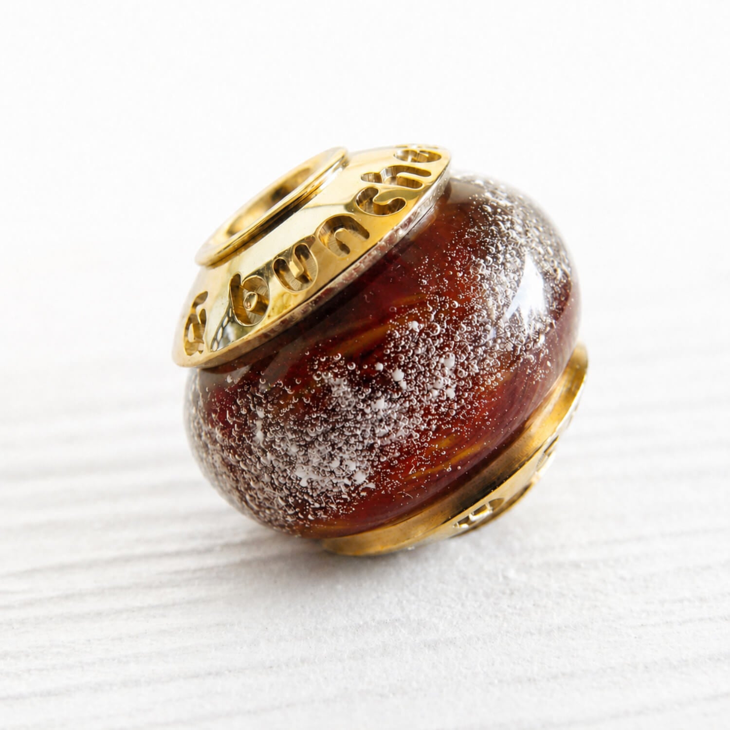 Swirls of dark red and orange hand blown glass under white specks of white ash set with 14k gold custom engraved bead caps