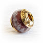 Dark red glass bead containing pet ashes with custom engraved 14k gold bead caps