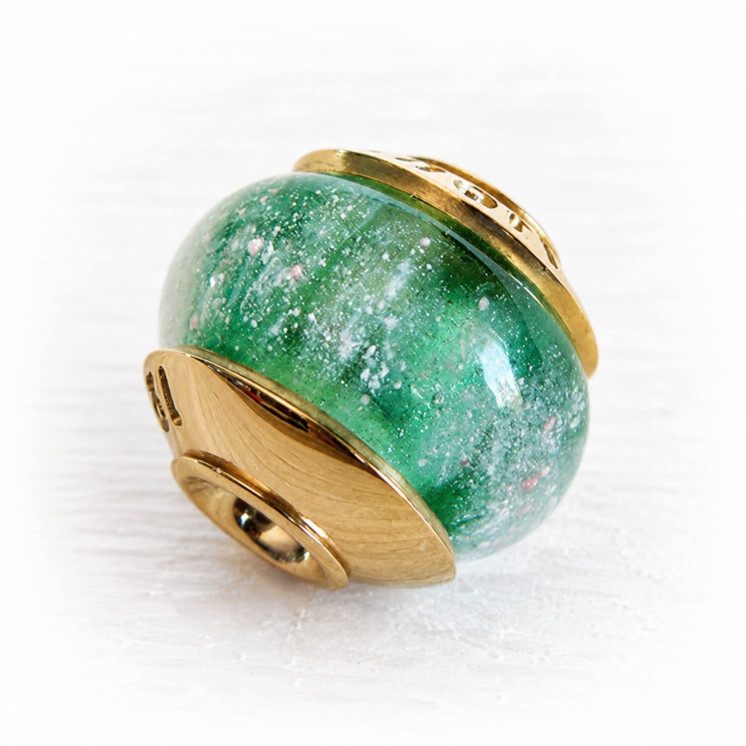 White specks of pet ash floating over sparkling green glass set in 14k gold