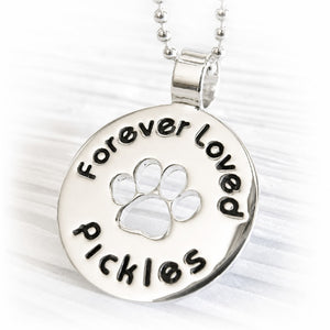 Remembrance jewelry for a lost pet with personalized engraving and a paw print cutout 