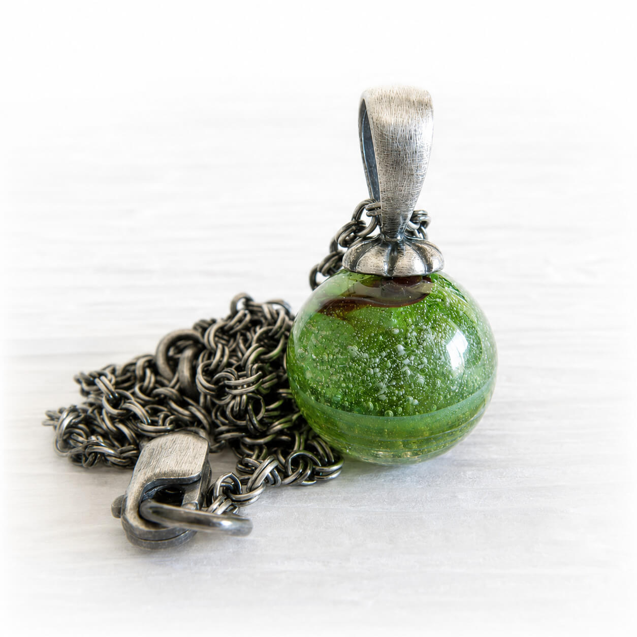 Green glass ash pendant on a sterling silver necklace with an antique finish