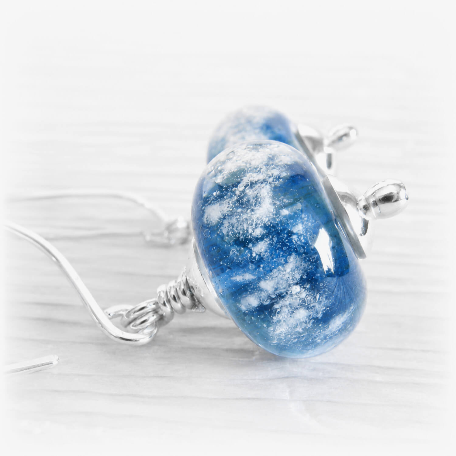 Swirling blue cremation bead drop earrings accented with silver end caps and french hooks